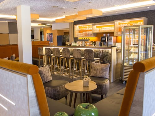 Bar im Hotel mit Barhockern, Kuchenbuffet und Sitzgelegenheiten