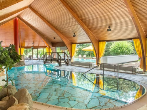 Poollandschaft im Haus mit kleiner Brücke und Relaxliegen am Rande
