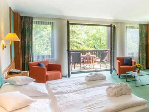 Doppelzimmer mit Doppelbett, Sesseln, Tisch, Balkon und Terrassenmöbeln