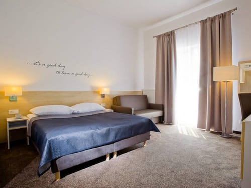 Doppelzimmer mit Doppelbett, Sessel und Stehlampe