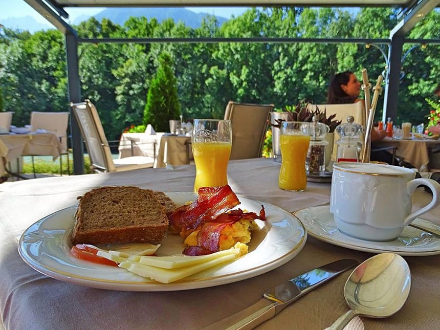 Speisenteller mit Brot, Käse. Ei und Speck auf der Hotelterrasse