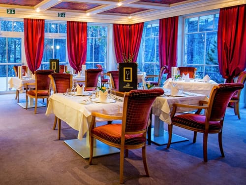 Hotelrestaurant mit weiß eingedeckten Tischen und rot gepolstertern Stühlen