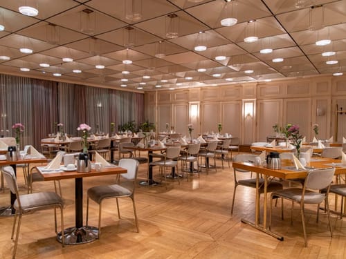 Elegantes Hotelrestaurant mit gedeckten Tischen und stimmungsvoller Beleuchtung