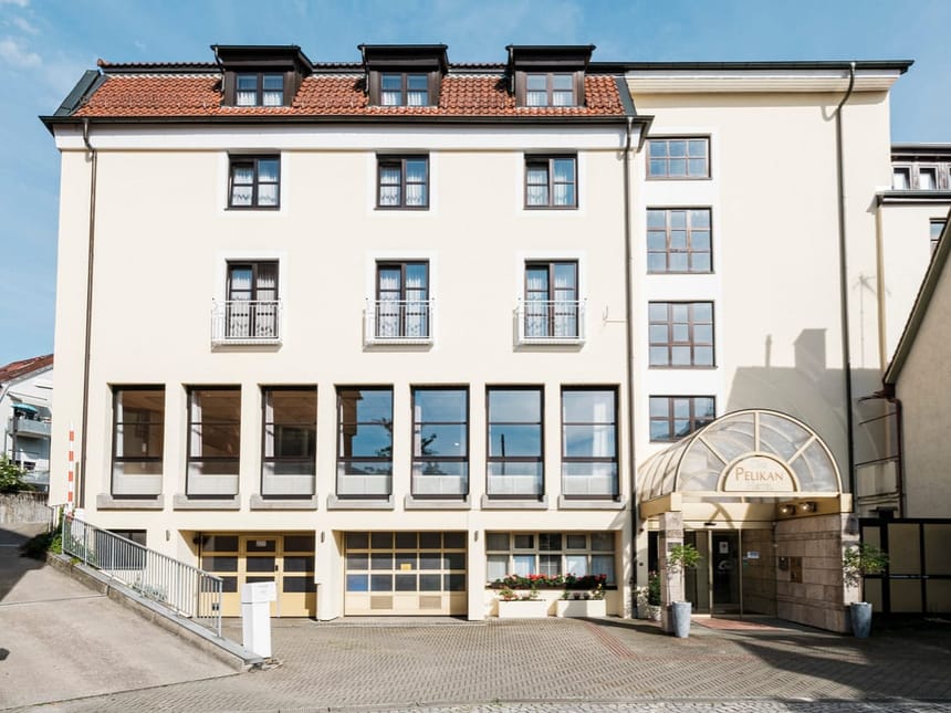 Außenansicht eines mehrstöckigen Hotels mit hellbeiger Fassade und großen Fenstern