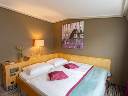 Gemütliches Hotelzimmer mit Doppelbett, stilvoller Beleuchtung und Wandkunst