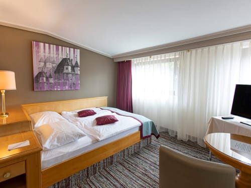 Gemütliches Hotelzimmer mit Doppelbett, Holzmöbeln und stilvoller Dekoration.