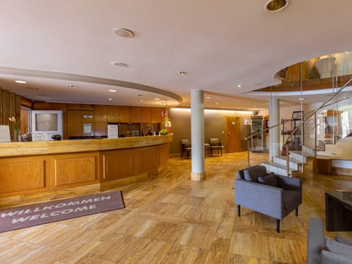 Helles und einladendes Hotellobby-Interieur mit Rezeption und Treppenaufgang.