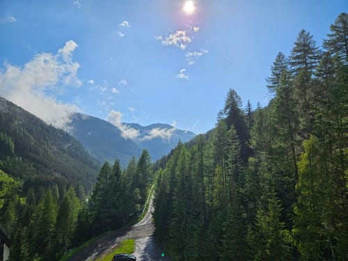 Malerische Berglandschaft mit dicht bewaldeten Hügeln unter strahlend blauem Himmel.