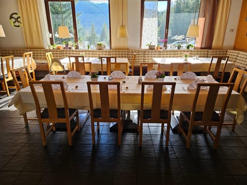 Gemütliches Restaurant mit Bergblick und elegant gedeckten Tischen.