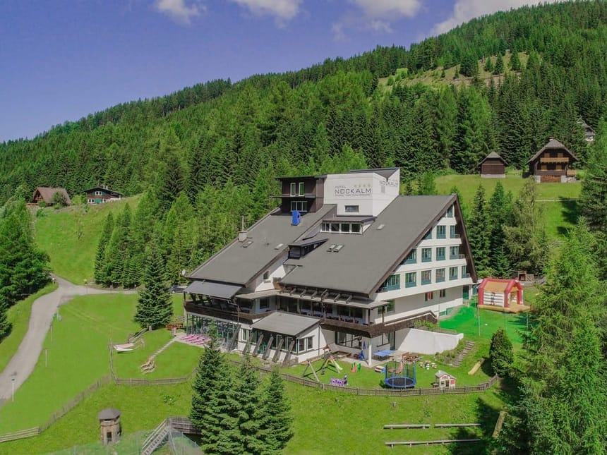 Hotel in malerischer Berglandschaft mit umliegenden Wäldern.