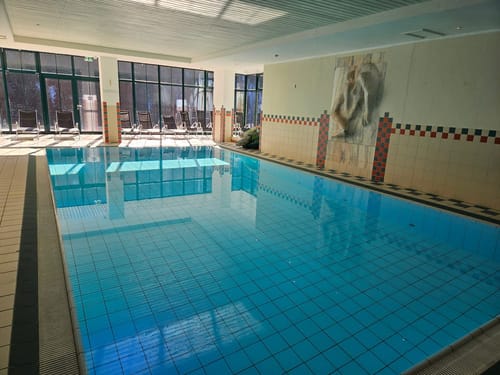 Entspannendes Hallenbad mit Liegestühlen und großen Fenstern.