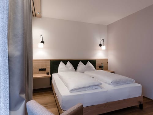 modernes Doppelzimmer mit Doppelbett, Wandlampen und Sessel