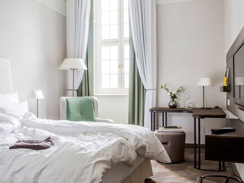 Modernes Hotelzimmer mit gemütlichem Bett, Schreibtisch und großen Fenstern.