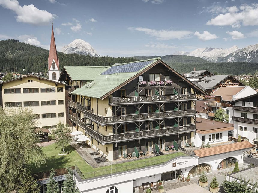 Hotelansicht bei Sonnenschein mit verschneiten Bergen im Hintergrund