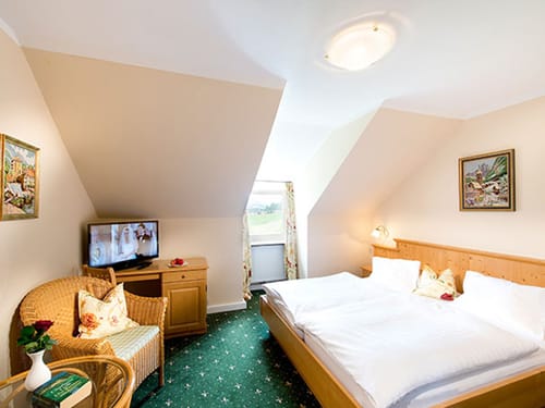 Doppelbett, TV, Sessel und Tisch im Doppelzimmer