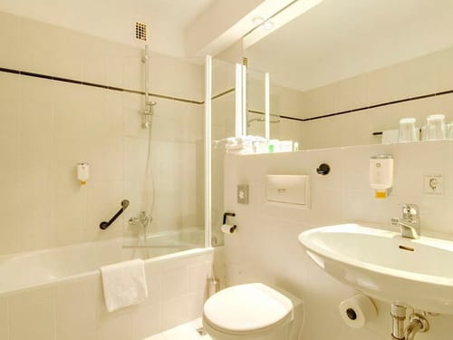 Badbereich mit Badewanne, großem Wandspiegel, WC und Waschtisch