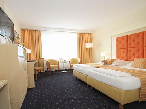 Twinbett, zwei Stühle, Tisch, Stehlampen und Schreibtisch im Doppelzimmer