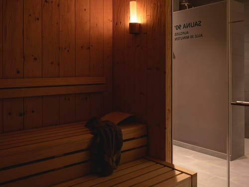 Innenansicht einer holzvertäfelten Sauna mit warmer Beleuchtung und Sitzbank.