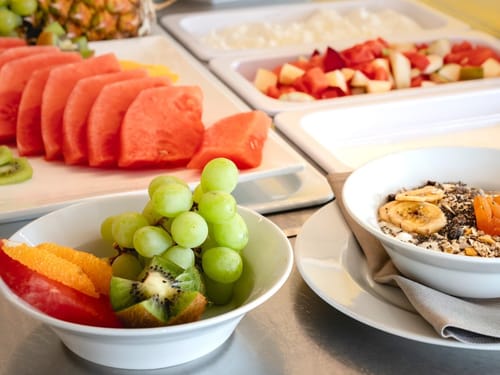 Verschiedene frische Früchte und Müsli auf einem Frühstücksbuffet.