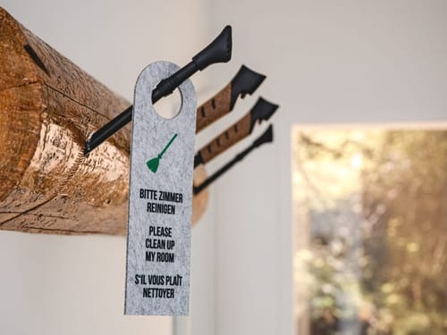 Türanhänger mit der Aufschrift "Bitte Zimmer reinigen" auf einem Asthalter.