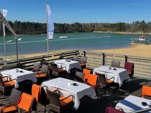 Ein herrlicher Blick auf einen türkisblauen See mit Sandstrand und Wald unter strahlend blauem Himmel.