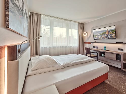 Modernes Hotelzimmer mit komfortablem Bett und großem Fenster