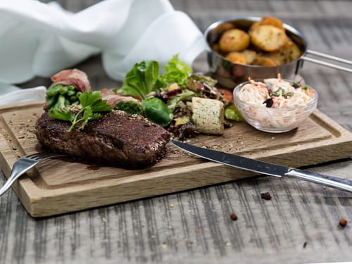 Entrecote mit Beilagen auf einem Speisenbrett angerichtet