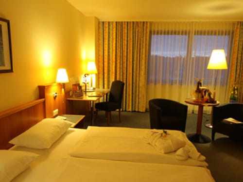 geräumiges Doppelzimmer mit Doppelbett, Schreibtisch, Stühlen, Tisch und Stehlampe