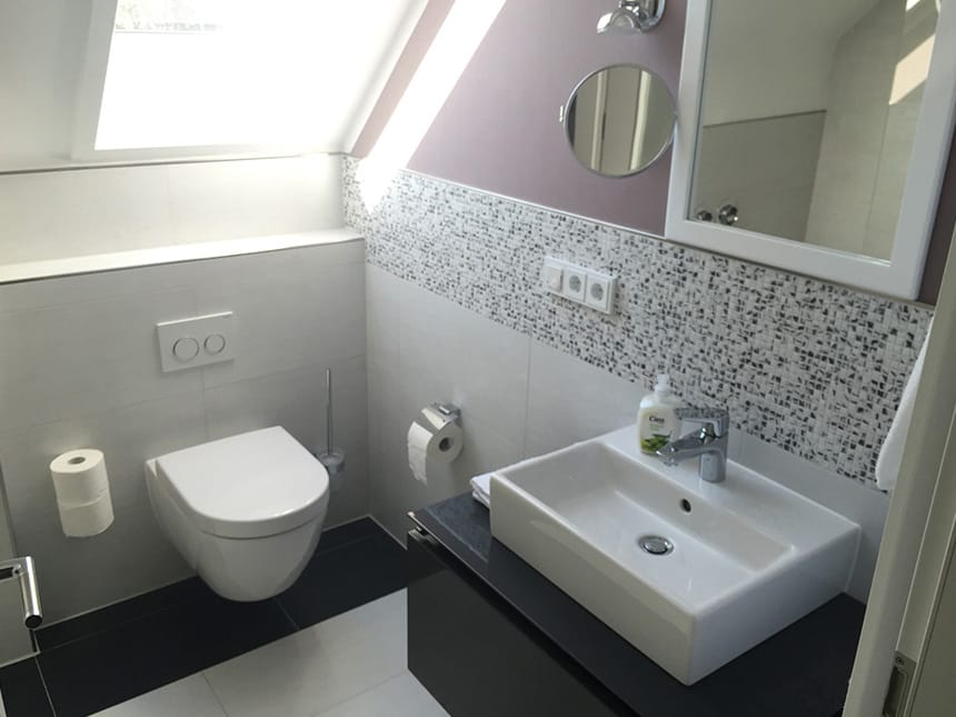 Badbereich mit Waschtisch, WC, Wandspiegel und Waschtisch