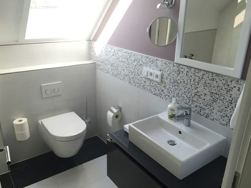 Badbereich mit Waschtisch, WC, Wandspiegel und Waschtisch