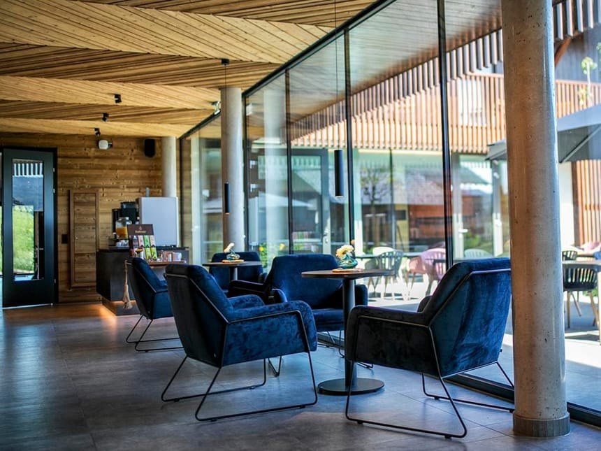 Moderner Loungebereich mit blauen Sesseln und großen Glasfenstern.