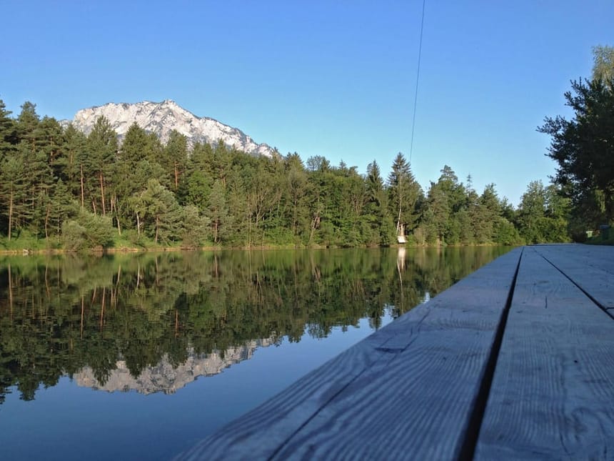 Ruhiger See mit Bergpanorama und Steg im Vordergrund