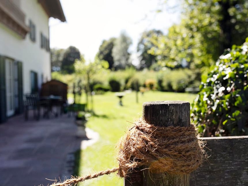 Nahaufnahme eines rustikalen Zaunpfostens mit Seil im sonnigen Garten