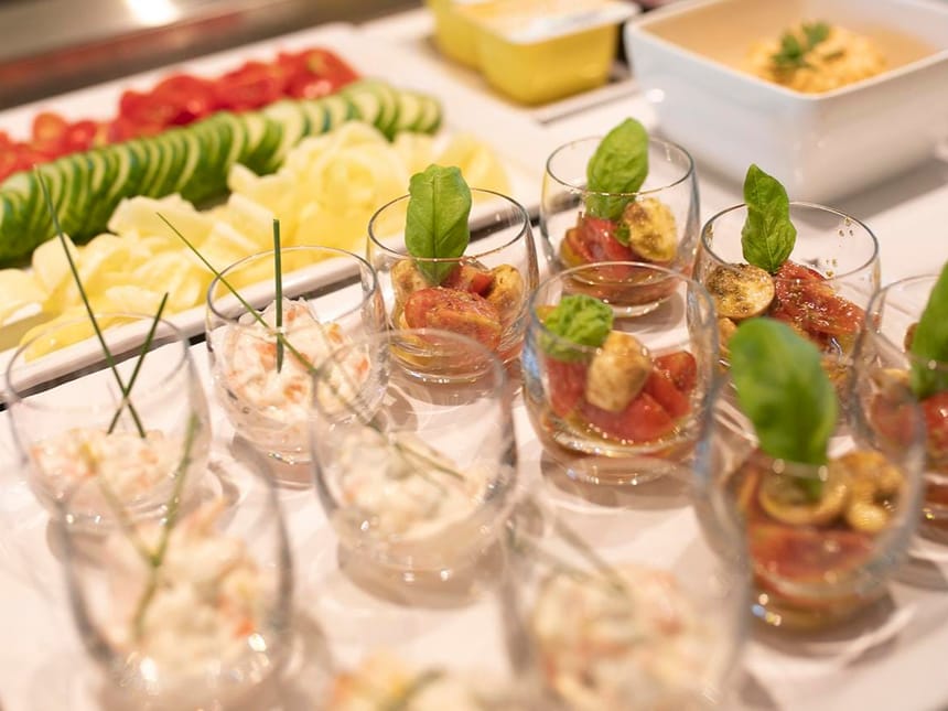 Appetitanregende Vorspeisen auf einem Buffet: Frische Gemüsescheiben und kreative Gläser mit Salaten.