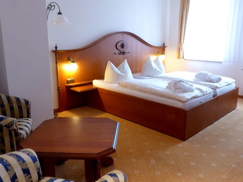 Doppelzimmer mit Doppelbett, Sessel und Tisch
