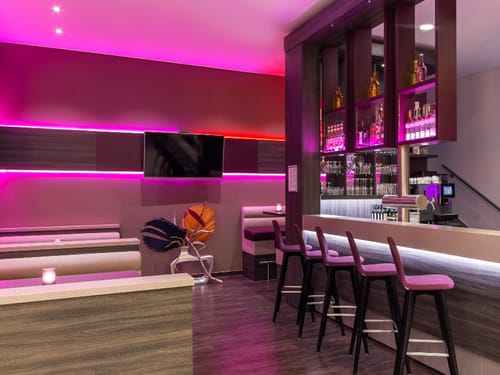 moderne Bar mit Barhocker, Theke und verschiedene Tischgruppen