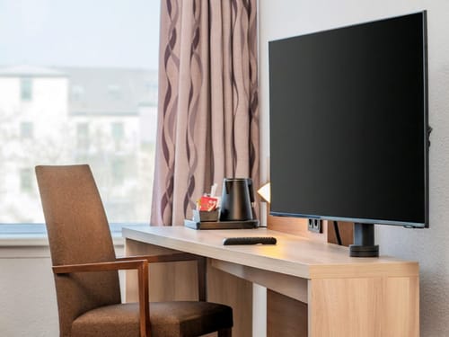 Moderner Hotelzimmer-Arbeitsbereich mit großem Flatscreen-TV und Holzschreibtisch