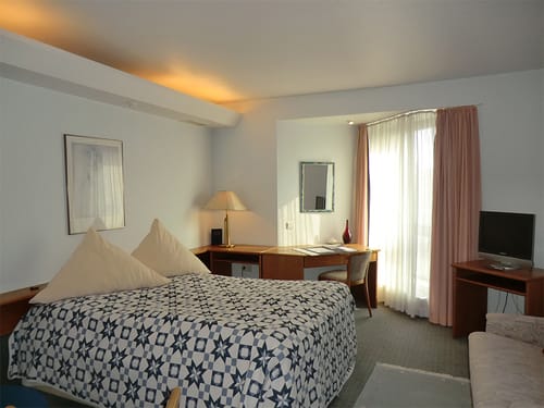 geräumiges Doppelzimmer mit Boxspringbett, Schreibtisch, TV, Stuhl und Couch
