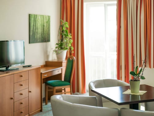 Doppelzimmer mit Sesseln, Tisch, Schreibtich, TV und Stuhl