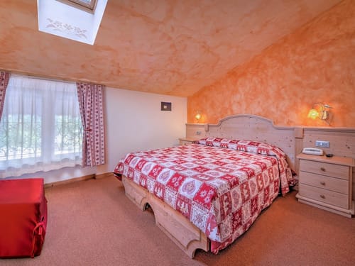Gemütliches Schlafzimmer mit rustikaler Holzeinrichtung und roter Bettdecke.
