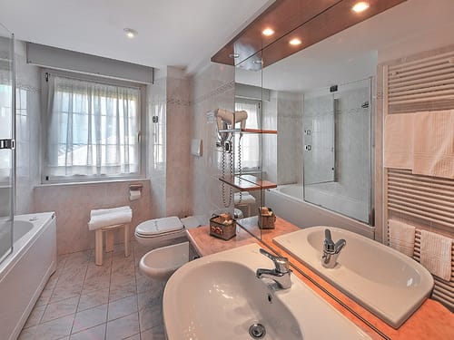 Modernes Badezimmer mit Doppelwaschbecken, Badewanne und großen Spiegeln.