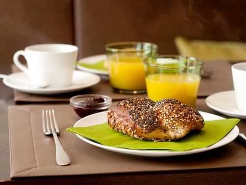 gedeckter Frühstückstisch mit Brötchen, Saft. Marmelade und Kaffee