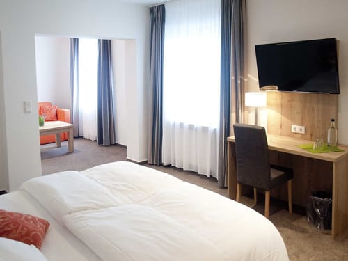 geräumiges Doppelzimmer mit Doppelbett, TV und Loungebereich
