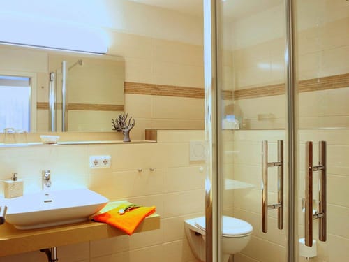 Dusche, Waschtisch und Wandspiegel im Bad