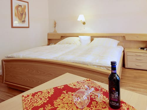 Doppelbett und Tisch mit einer Flasche Wein