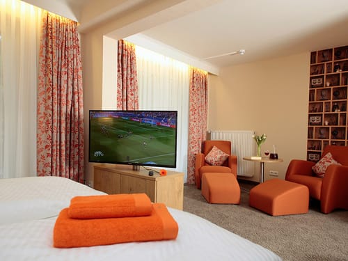 zwei Fernsehsessel mit Tisch sowei ein Doppelbett und TV