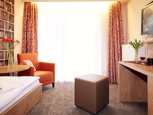 Bett, Tisch, Sessel, Hocker und Schreibtisch im Zimmer