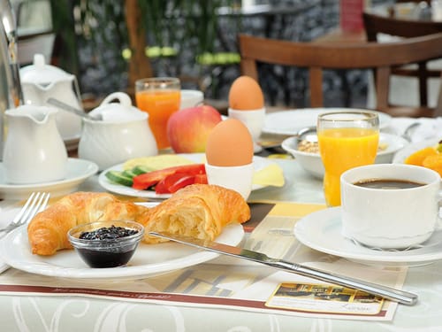Marmelade, Croissant, Ei, Saft und Kaffee auf dem Frühstückstisch