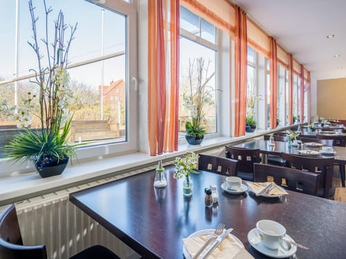 Helles Restaurant mit großen Fenstern und elegant gedeckten Tischen.