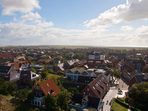 Luftaufnahme eines malerischen Küstendorfs mit roten Ziegeldächern und weitläufiger Landschaft im Hintergrund